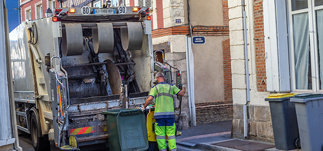 Éboueur en ville avec le camion poubelle